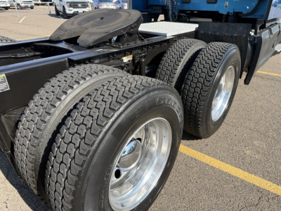 Peterbilt 579 rear wheels and chassis showing dual rear axles and tires with chrome rims; fuel cell area and fifth wheel visible in the background.