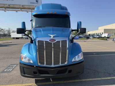 Peterbilt 579 truck front view showing large chrome grille, blue hood with Peterbilt emblem, and black bumper.
