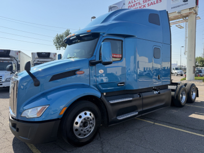 Peterbilt 579 truck in blue, front-left view showing hood, windshield, door, and side mirror with Peterbilt emblem. No visible model decals readable.