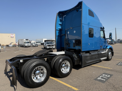 Peterbilt 579 truck cab in blue with sleeper, rear view shows dual rear axles and fifth wheel, side view shows VIN and stock number not visible on image