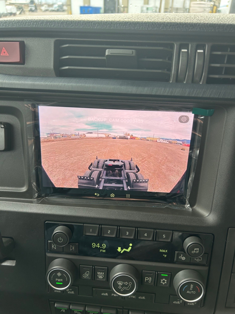 Volvo VNL64T860 dashboard view showing infotainment screen with backup camera display, climate and media controls, and hazard switch.