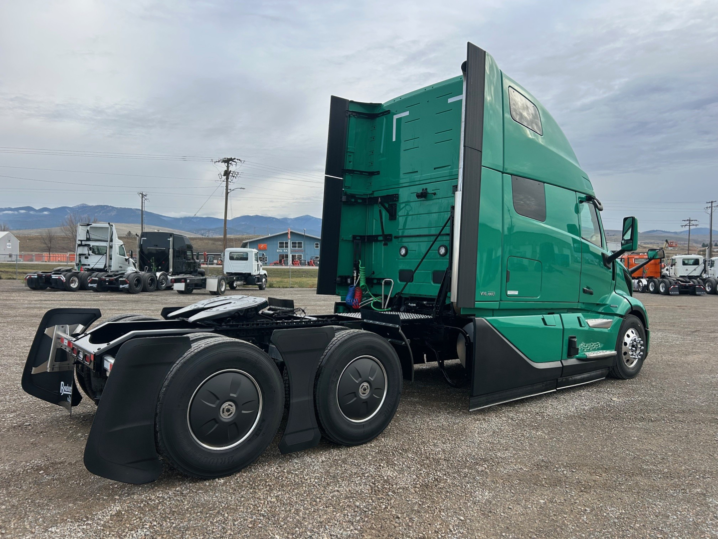 Volvo VNL64T860 sleeper cab tractor side view showing green paint, aerodynamic mirrors, and dual rear axles with black fenders.