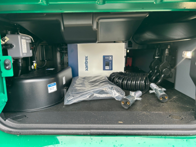 Volvo VNL64T860 storage area under cab showing Xantrex power unit box and cables in storage compartment.