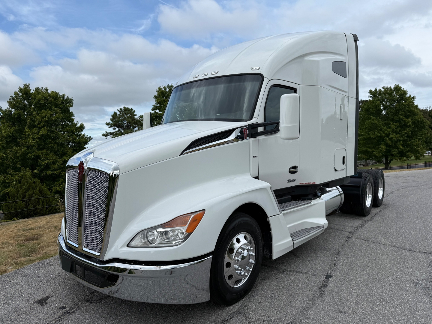 Kenworth T680 conventional sleeper truck, white cab, side view showing chrome grille, hood, and dual rear axles.