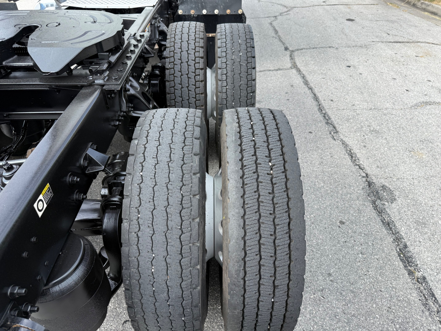 Kenworth T680 chassis showing dual rear axles and tires with tread, side view of drivetrain and frame.