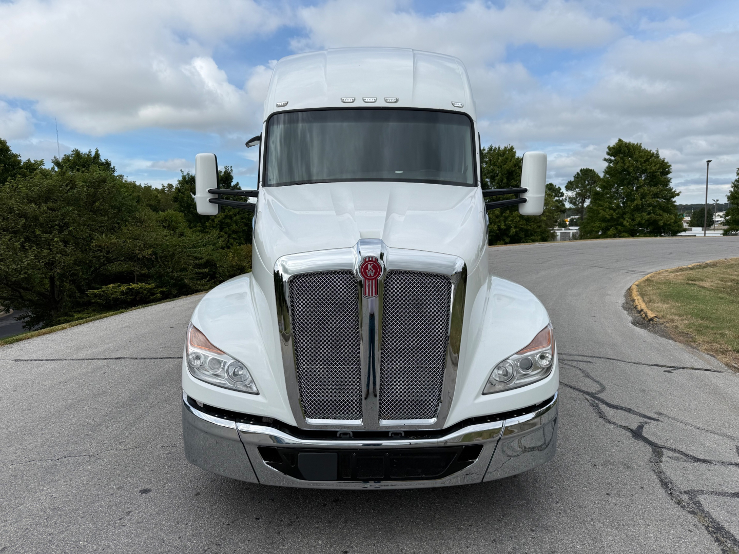 Kenworth T680 conventional sleeper front view showing chrome grille and large bumper, white exterior.