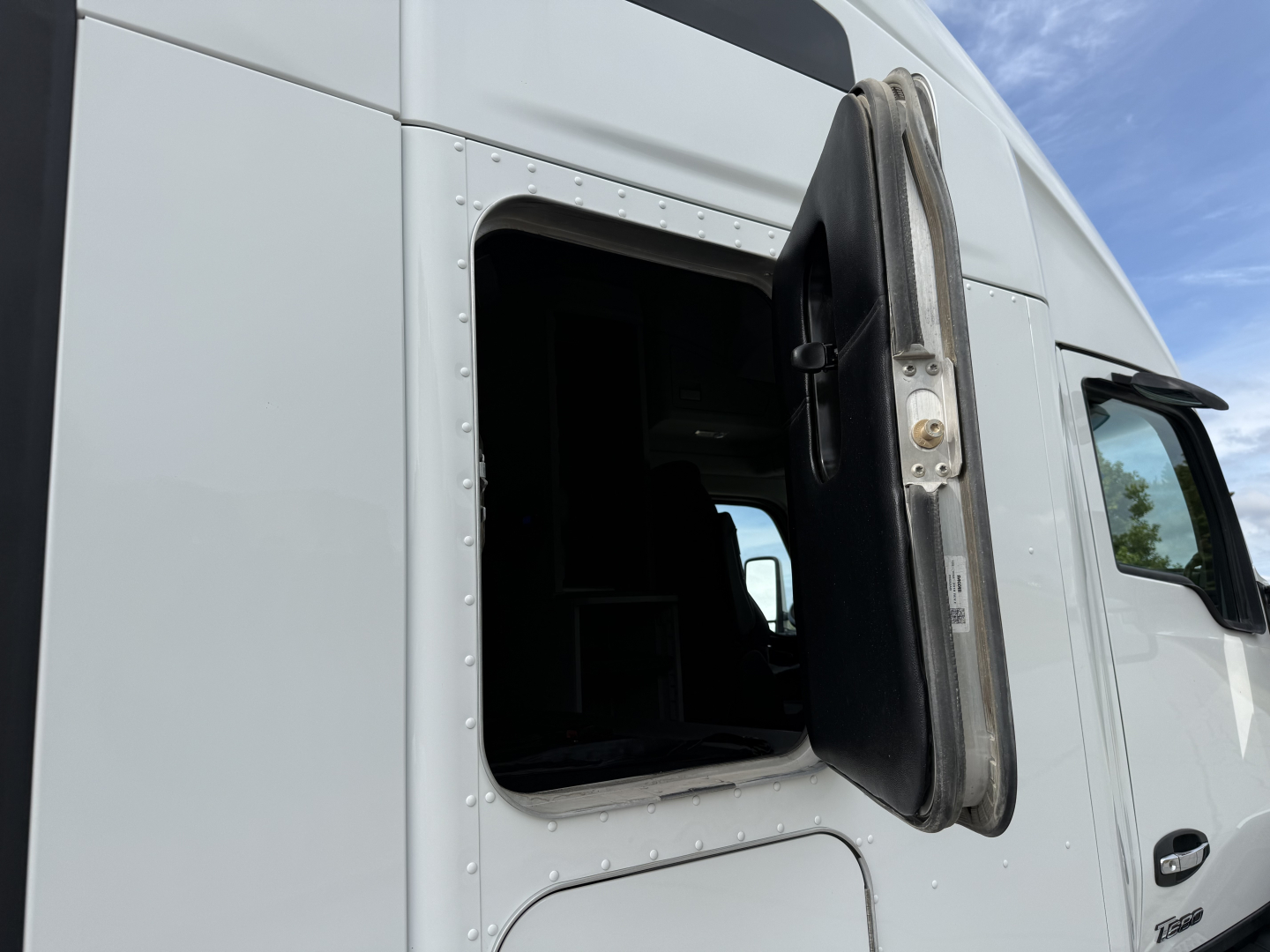 Kenworth T680 truck cab door open showing side of sleeper, plain white exterior.