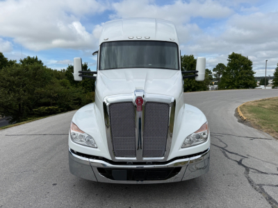 Kenworth T680 conventional sleeper front view showing chrome grille and large bumper, white exterior.