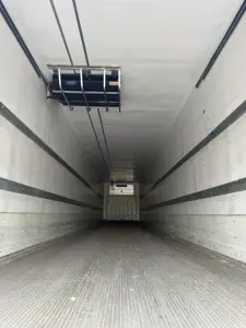 Interior of refrigerated trailer showing insulated walls, ceiling ceiling liner, side rails, and rear ramp door in cabin; no readable labels visible.