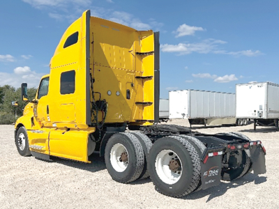 International LT625 conventional sleeper truck shown in side-angle rear view with bright yellow cab and dual rear axles.