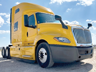 International LT625 semi truck front-left view showing yellow tractor with chrome grille and black bumper, air intake, and dual rear axles.