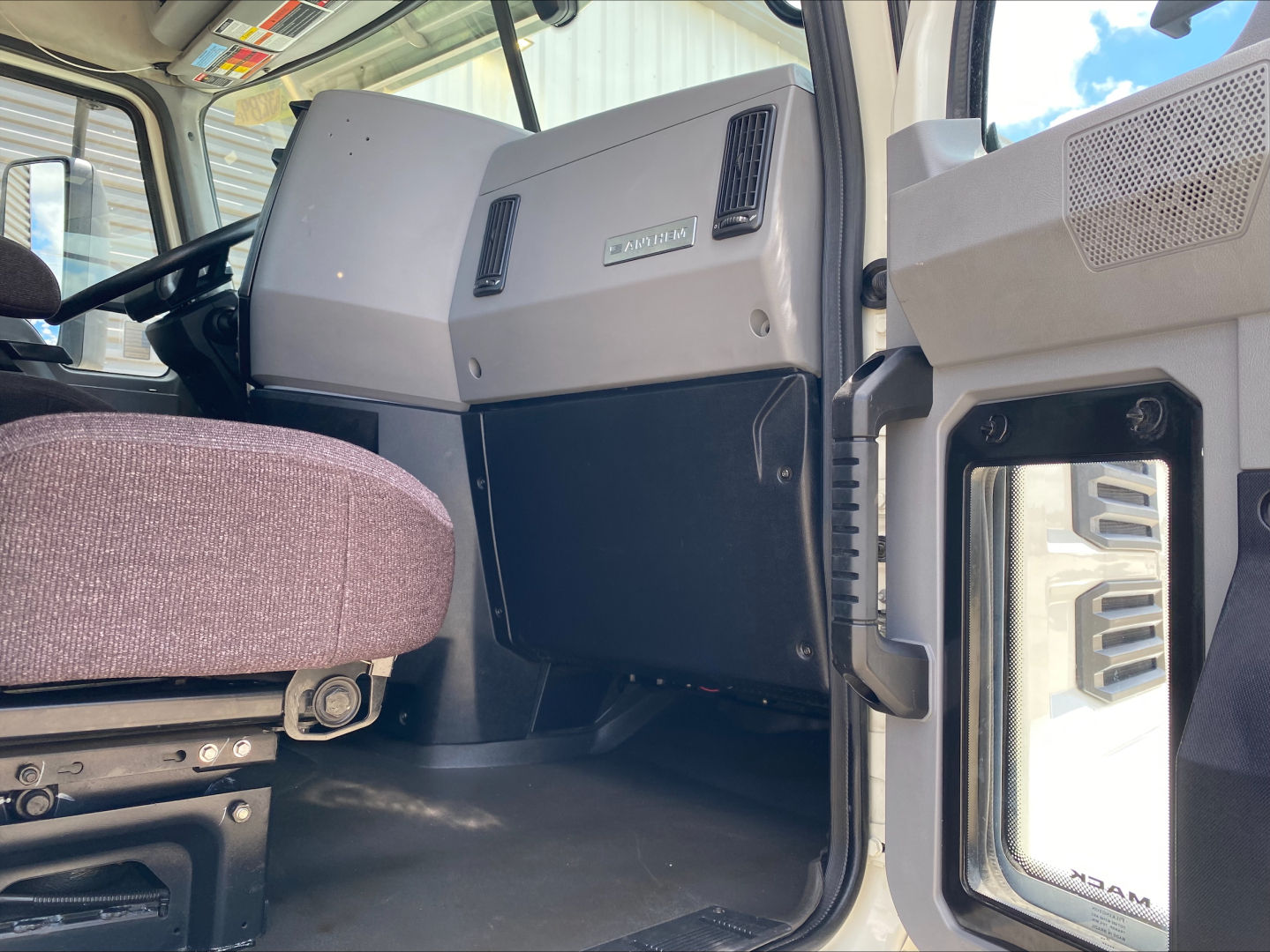 Cab interior of 2021 Mack AN64T truck showing dashboard with large panels, steering column, and driver seat.