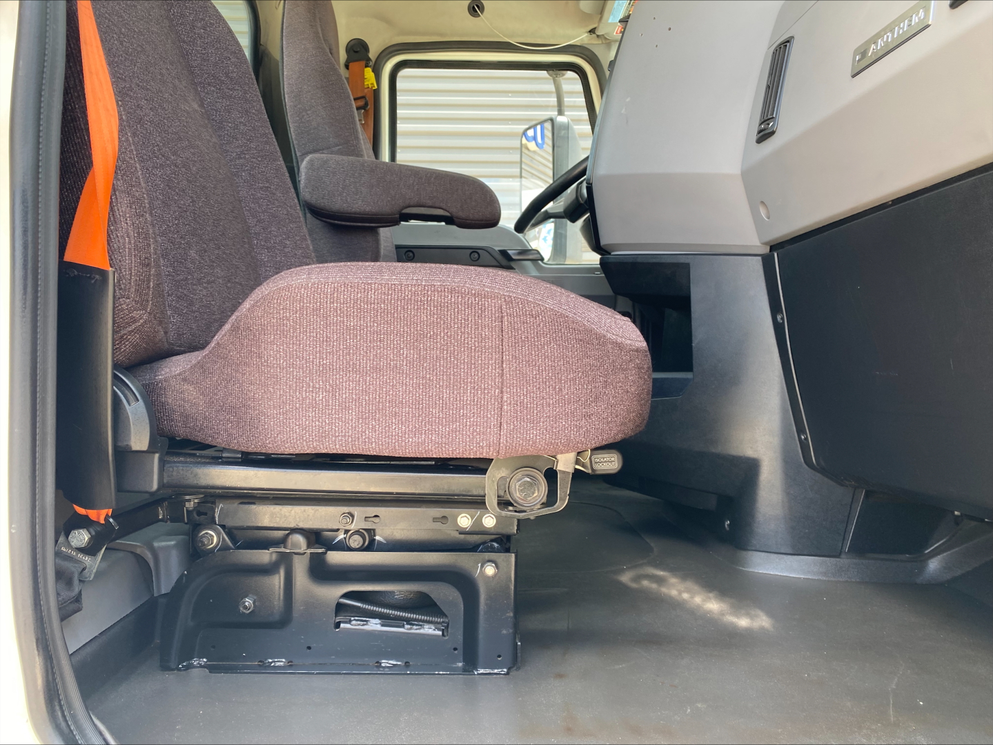 Mack AN64T cab interior showing front seat and driver controls, grey dashboard, and floor area in service seat position.