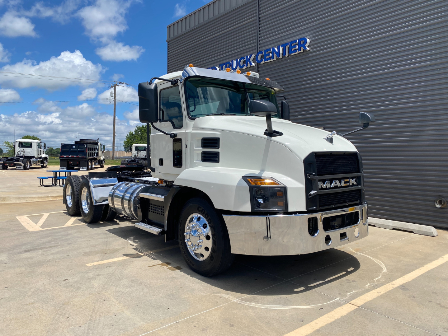 White 2021 Mack AN64T conventional day cab truck parked outside a building with chrome bumper and dual rear axles.