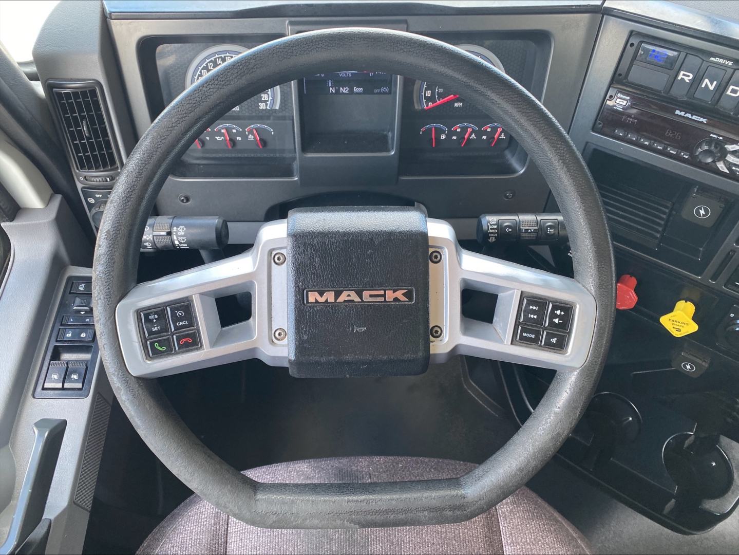 Mack AN64T truck cabin view focusing on steering wheel with Mack logo and dashboard controls.