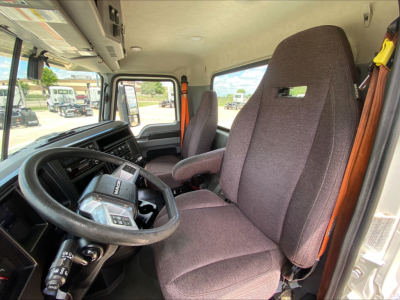 Truck cab interior with steering wheel, driver seat, and passenger seat in view. dashboard and control stalks visible.