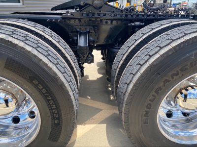 Truck axle area showing dual rear wheels (tandem) on a Mack AN64T chassis with chrome wheels and tire tread visible.