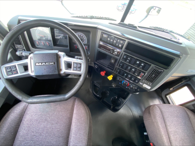 Mack AN64T truck cab interior showing steering wheel with Mack logo, dashboard controls, and center instrument cluster.