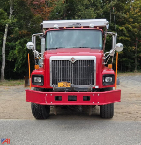 Front view of a red 2011 International DF567 PayStar 5600i dump truck with plow and sander, chrome grille, yellow license plate, and large side mirrors.