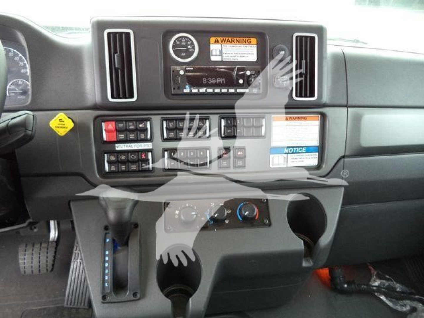 Dashboard of a Freightliner M2 106 cab showing center control panel and gauges with warning labels.
