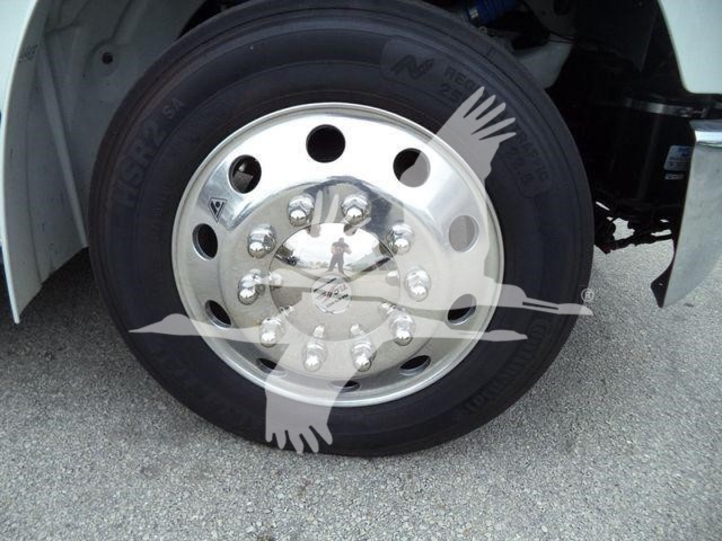Wheel close-up of a Freightliner M2 106 truck showing a polished chrome hubcap with multiple lug nut bolts and NITRO tires.