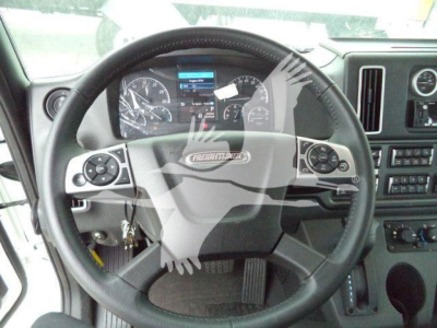 Steering wheel and dashboard view inside a Freightliner M2 106 cab showing steering wheel controls and instrument cluster.