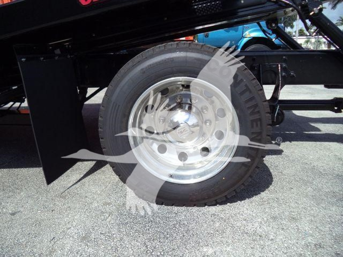Truck wheel and tire assembly on a rollback truck viewing the rear wheel and part of the frame with a shiny metal rim.