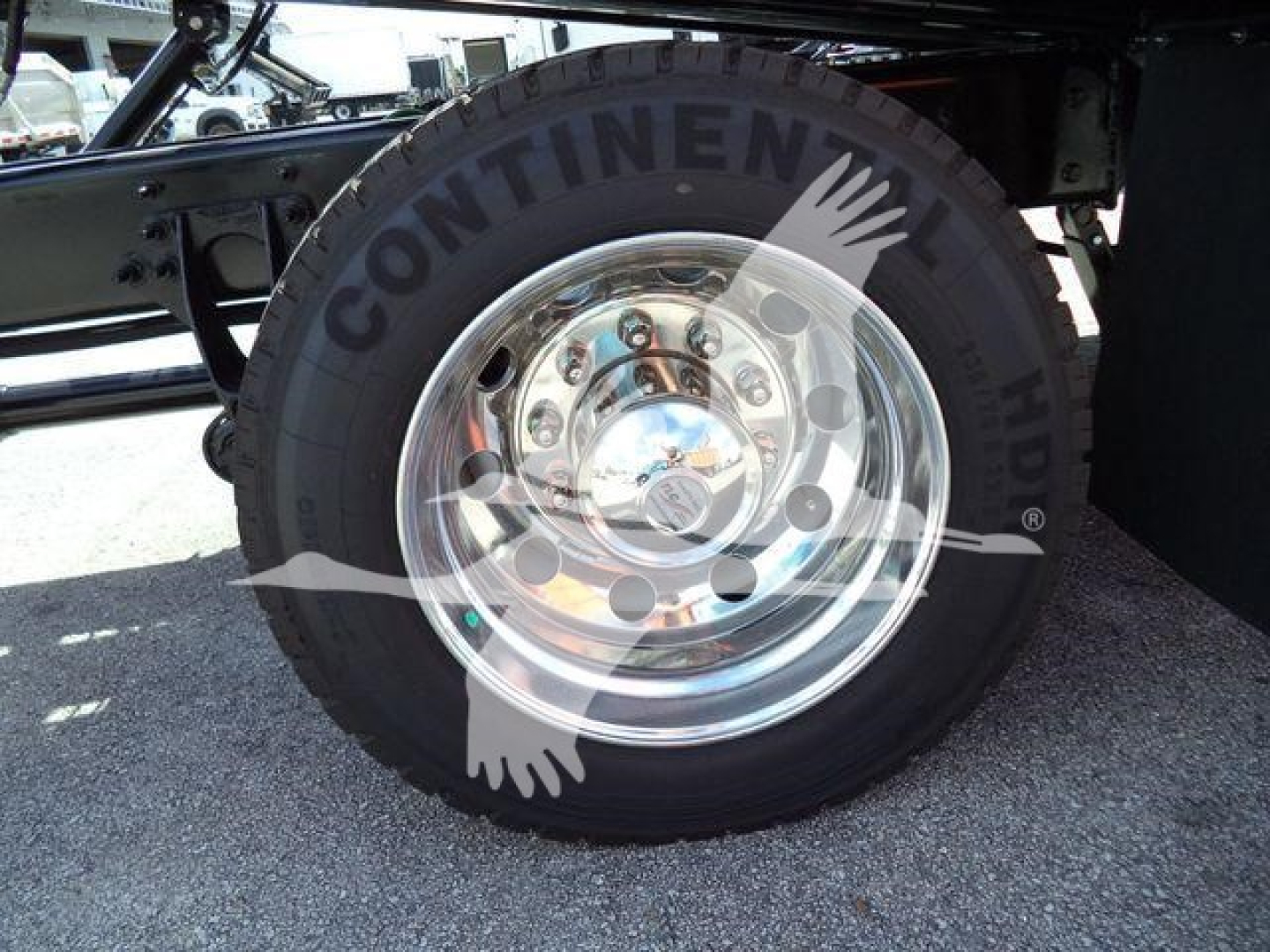 Truck wheel with Continental tire and polished chrome hub showing axles and suspension components.