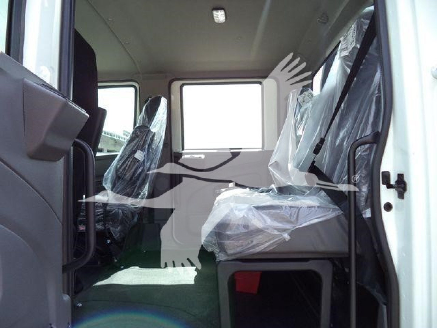 Interior of a 2026 International MV cab showing plastic-covered seats and green floor with seating area visible.