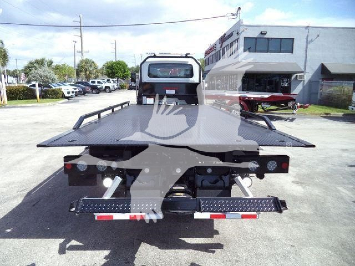 Flatbed tow truck bed on a rollback trailer with rear lights and loading ramps visible.