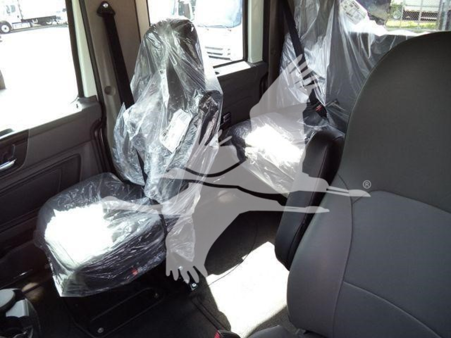 Interior of truck cab with plastic-wrapped seats and seating area visible.