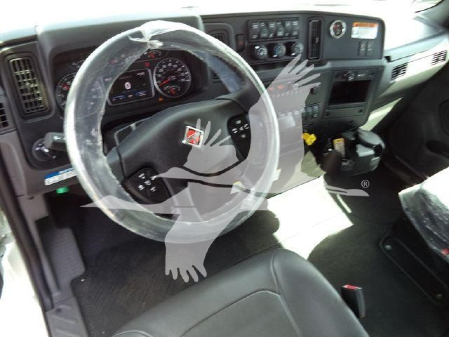 Interior of a truck cab showing steering wheel and dashboard with plastic cover over wheel and gear selector area.