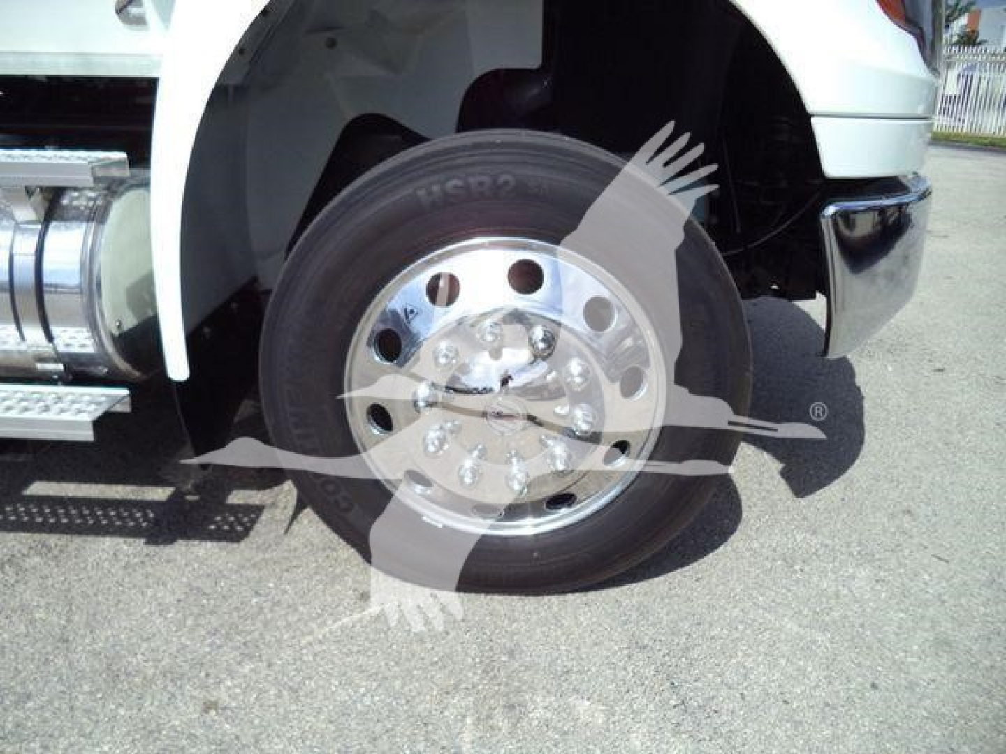 Truck wheel and front fender of a 2026 International MV rollback truck showing front axle, chrome hub, and tire details.