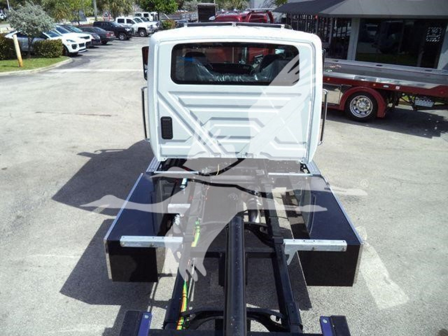 Truck chassis and cab of a 2026 International MV rollback body showing hydraulic lines and hitch components.