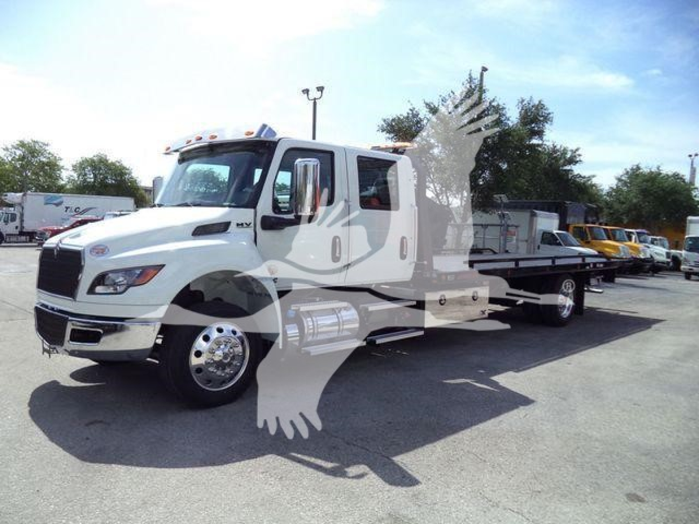 International MV truck in service bay showing cab and rollback service body, side fuel tanks, and chrome wheels.
