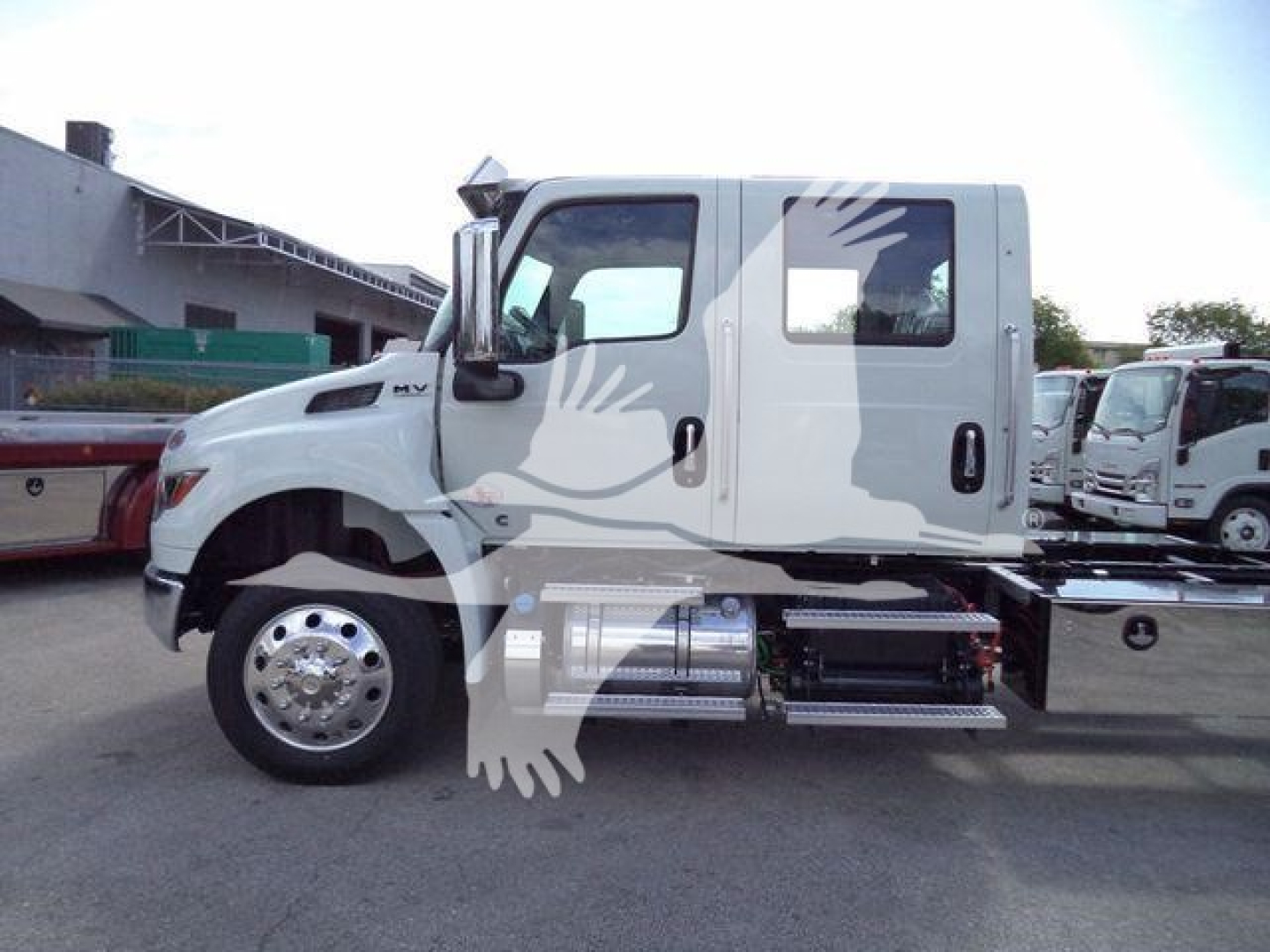 International MV truck side view showing dual rear wheels and chrome fuel tanks in rollback lot.