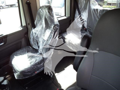 Interior of truck cab with plastic-wrapped seats and seating area visible.