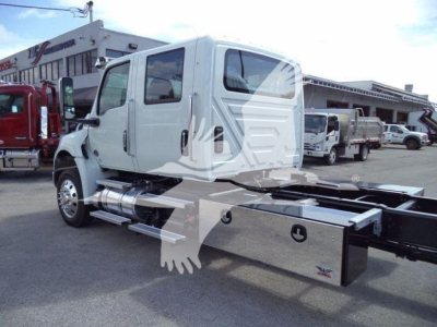 Truck cab with a booster platform in a dealership lot; MV Series International chassis with metallic chrome toolbox and side rails; stock number MVCREW22SRR6T visible.