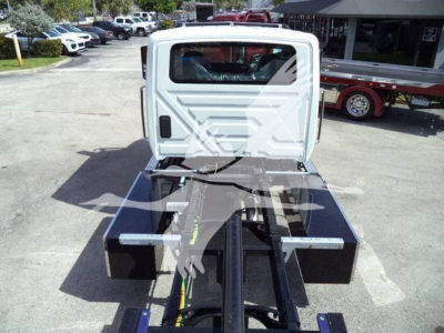 Truck chassis and cab of a 2026 International MV rollback body showing hydraulic lines and hitch components.
