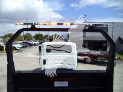 Trucking equipment rear view showing a Jerr-Dan rollback carrier with light bar on top; white cab visible through frame, black bed and frame components.