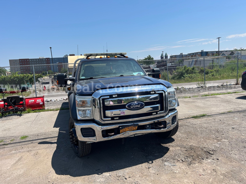 Ford F-550 flatbed truck front view showing chrome grille, Ford emblem, headlights, bumper, and orange warning light bar on roof.