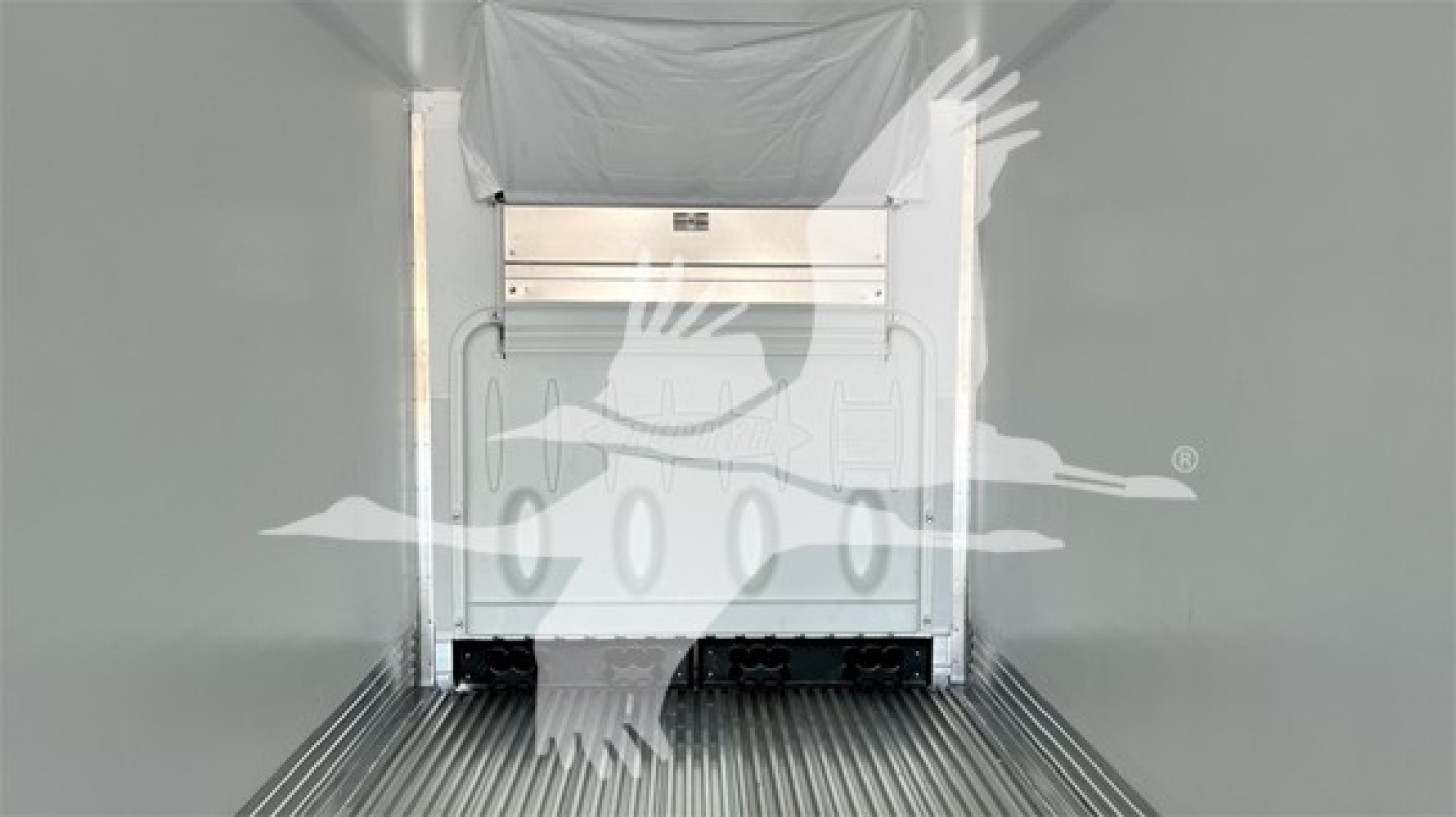 Rear interior of a refrigerated trailer showing loading door and stainless lower threshold with a logo watermark overlay; no legible model text visible.