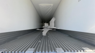 Trailer interior showing ribbed floor and narrow side walls with bright light at the far end; silhouette of a person jumping in white overlays the center.
