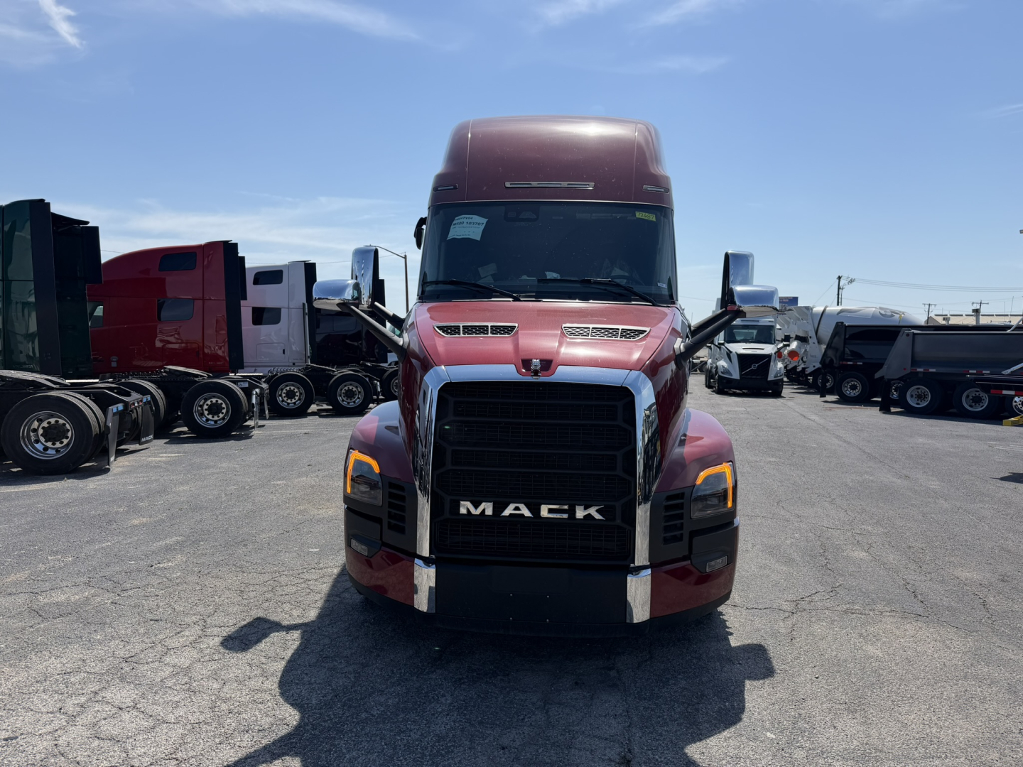 Mack PR64T76H conventional sleeper truck front view showing bold black grille with MAC K lettering, maroon cab, large bumper, daytime running lights.