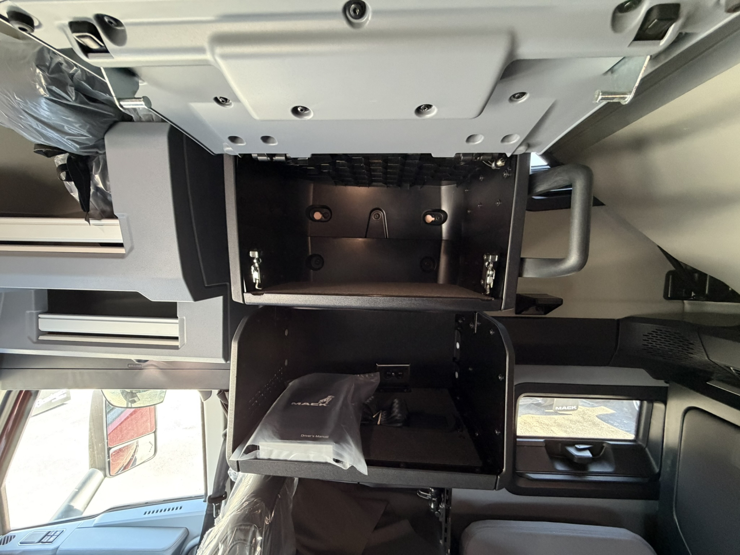 Cab interior of a Mack PR64T76H showing center console storage compartments and dashboard area.