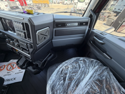 Interior cab view of a 2027 Mack PR64T76H truck showing steering wheel, dashboard with numerous switches, Pioneer infotainment, and plastic-covered driver seat.