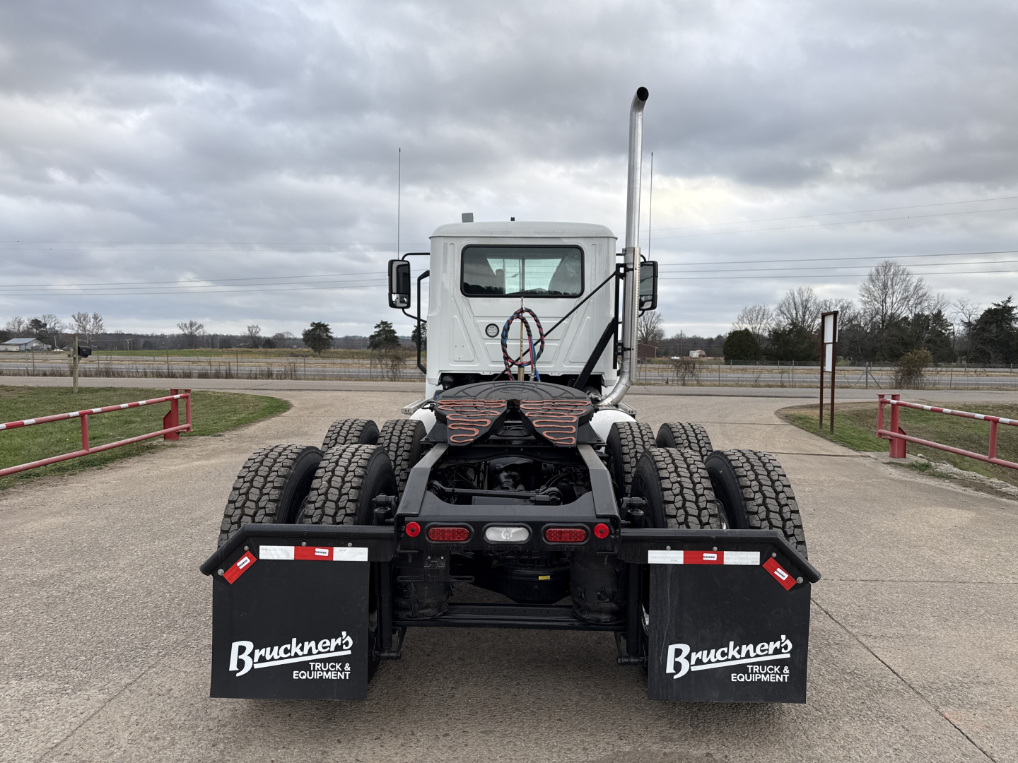 Truck chassis back view of a new Mack PI64T conventional daycab showing dual rear axles and mud flaps with Brückner's Equipment logos.