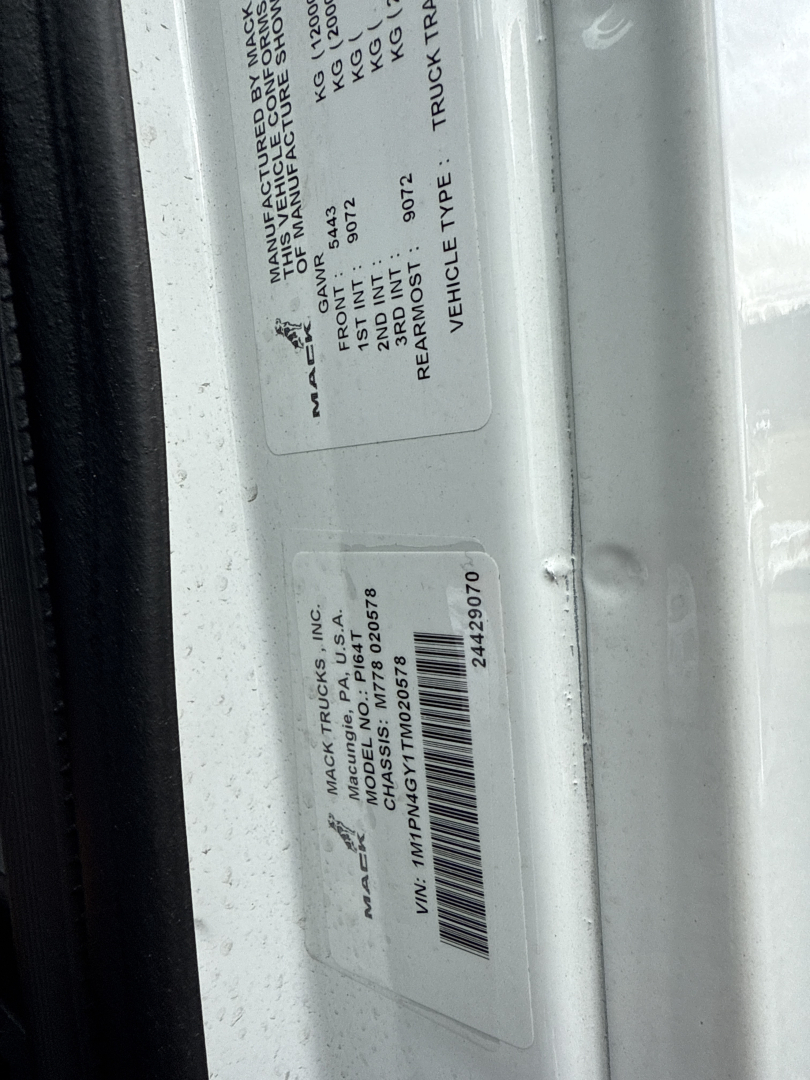 Label stickers on Mack PI64T door jamb with VIN/barcode and manufacturer information.