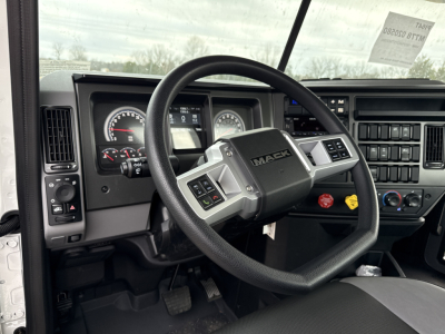 Dashboard and steering wheel of a Mack PI64T truck showing steering wheel with Mack logo, instrument cluster, and center console controls.