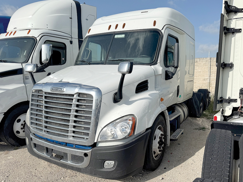 Freightliner Cascadia113 medium-duty tractor cab in a parking lot, front grille with chrome, large headlights, dual mirrors, white exterior, blue accent line on grille.